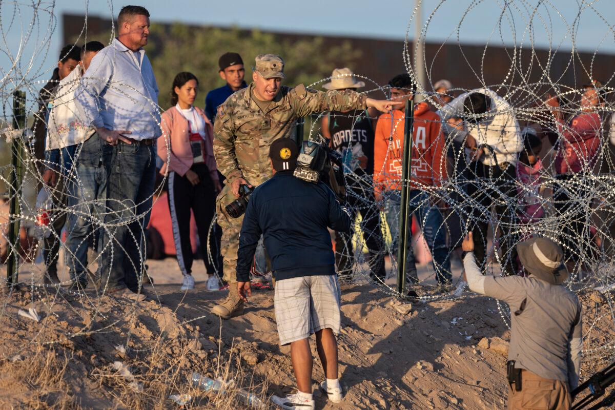 A Texas National Guard soldier bars journalists from approaching migrants who had crossed over from Mexico, in El Paso, Texas, on May 9, 2023. (John Moore/Getty Images)