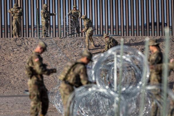 Texas National Guard soldiers uncoil concertina wire near the U.S.–Mexico border fence in El Paso, Texas, on May 10, 2023. (John Moore/Getty Images)