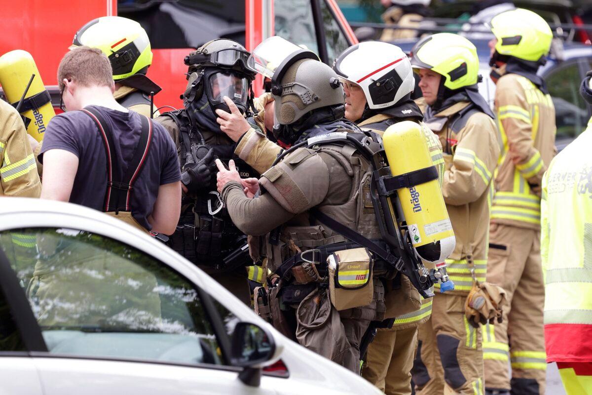 Police officer wearing gas masks and firefighters stand in front of a residential building in Ratingen, Germany, on May 11, 2023. (David Young/dpa via AP)