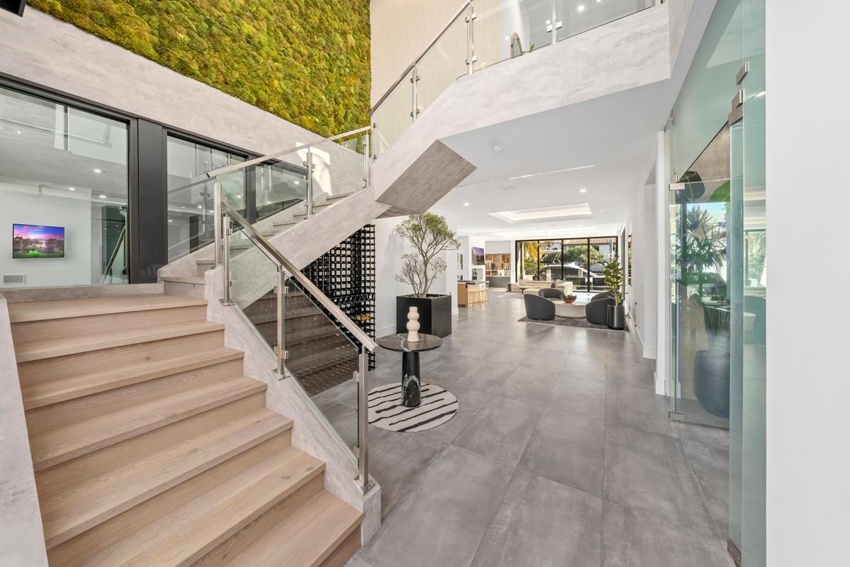 At the entry, a staircase leads to the bedrooms, while the open floorplan draws the eye to the living areas and pool beyond. (Luxury Production Studios / ONE Sotheby's International Realty)