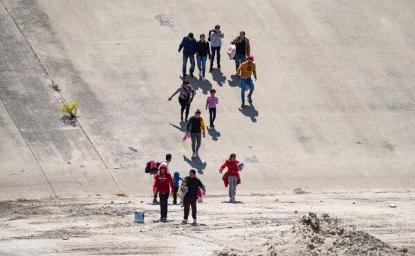 Migrants cross the Tijuana River bed towards the San Diego port of entry to the United States on May 11, 2023. (John Fredricks/The Epoch Times)