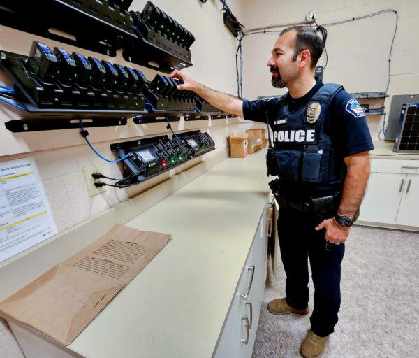 San Luis, Ariz., Police Lt. Marco Santana inspects batteries used in police body cameras on May 11, 2023. (Allan Stein/The Epoch Times)
