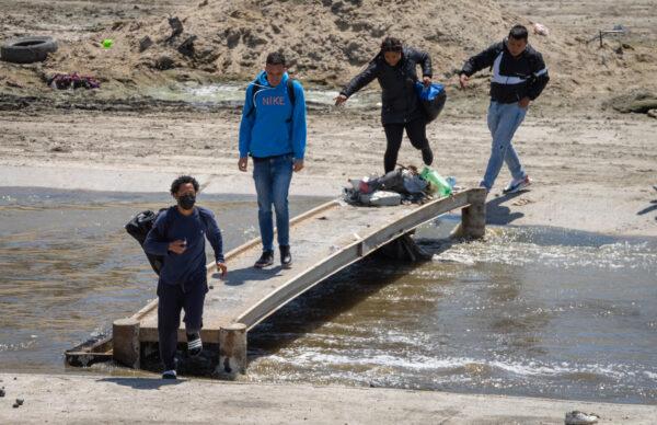Migrants cross the Tijuana River toward the U.S. border in Tijuana, Mexico, on May 11, 2023. (John Fredricks/The Epoch Times)