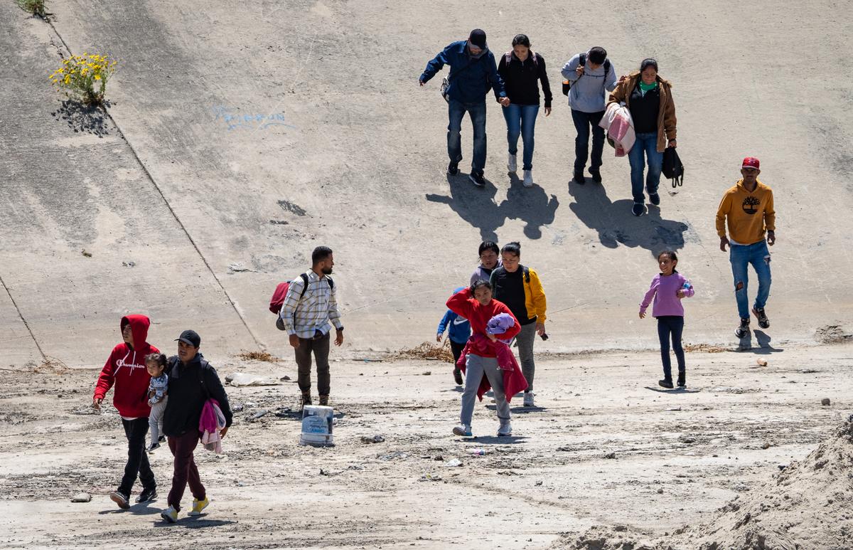 Migrants cross the Tijuana River toward the U.S.-Mexico border in Tijuana, Mexico, on May 11, 2023. (John Fredricks/The Epoch Times)