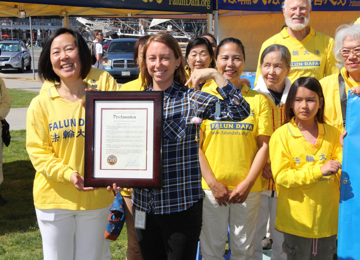 San Diego County Supervisor Joel Anderson’s Chief of Staff Maggie Sleeper holds lotus flower decorations as she presents a proclamation to Falun Dafa practitioners in San Diego on May 7, 2023. (Jane Yang/The Epoch Times)