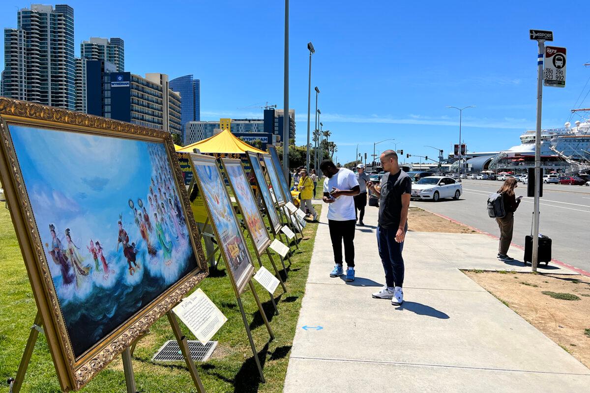 Bystanders look at paintings on display as members of the spiritual practice Falun Dafa celebrate World Falun Dafa Day at the San Diego County Administration building in Downtown San Diego on May 7, 2023. (Jane Yang/The Epoch Times)