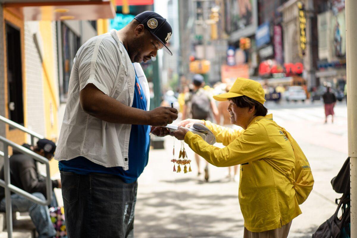 A Falun Gong practitioner collects signatures for a petition urging lawmakers to help stop forced organ harvesting from prisoners of conscience in China, during a parade to celebrate World Falun Dafa Day in New York on May 12, 2023. (Samira Bouaou/The Epoch Times)