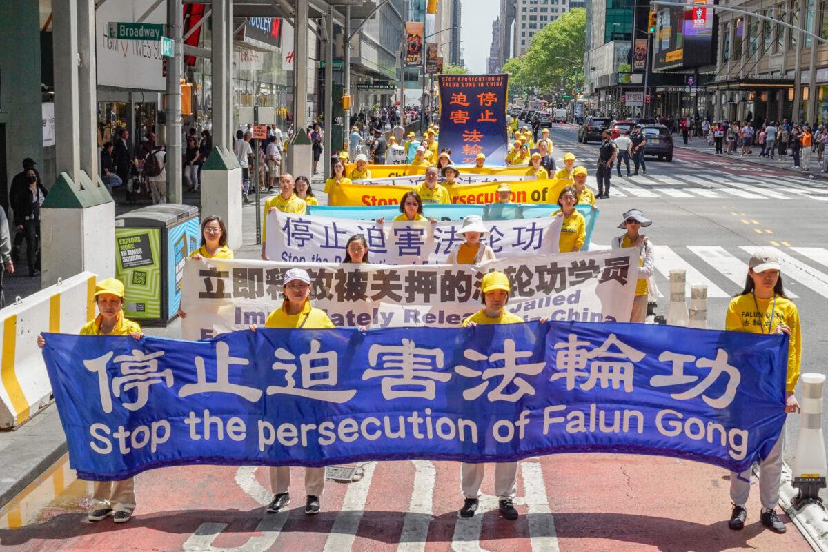 Falun Gong practitioners hold a banner raising awareness about the Chinese communist regime's persecution of their faith, during a parade to mark World Falun Dafa Day in New York on May 12, 2023. (Larry Dye/The Epoch Times)
