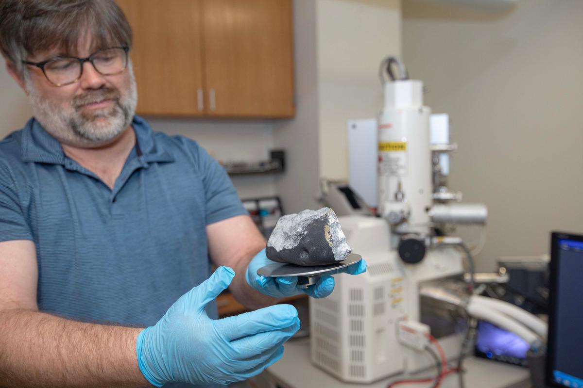 Nathan Magee, chair of The College of New Jersey’s Physics Department, holds up the “Titusville, NJ” meteorite on May 10, 2023. (Courtesy of Anthony DePrimo via The College of New Jersey)
