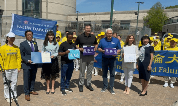 Barrie city councillor Nigussie Nigussie (centre L), Barrie Mayor Alex Nuttall (centre), and Conservative MP John Brassard (centre R) pose with hosts and Falun Dafa practitioners during a World Falun Dafa Day flag-raising event in Barrie, Ont., on May 13, 2023. (The Epoch Times)