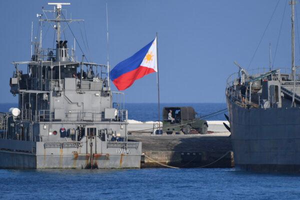 A Philippine flag flutters next to navy ships anchored at the Philippine-occupied Thitu island in the disputed South China Sea, on April 21, 2023. (Ted Aljibe/AFP via Getty Images)
