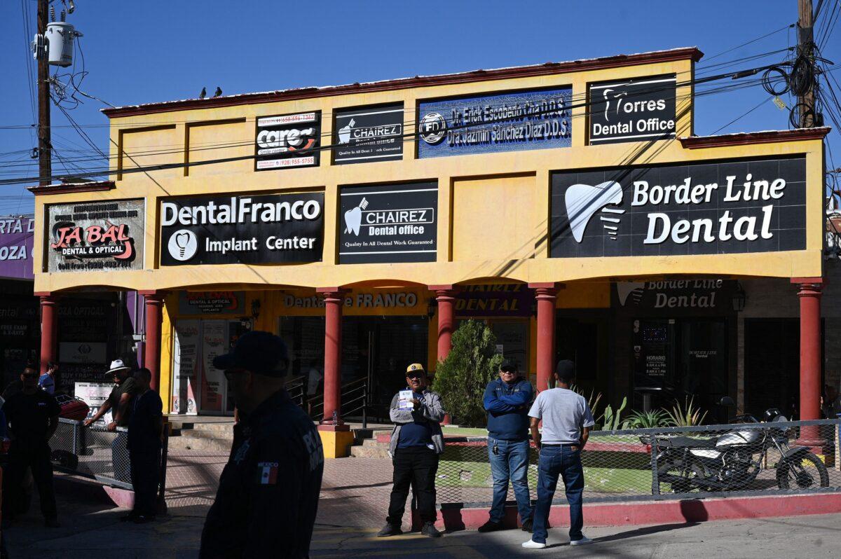 A man holds a sign advertising dental services as he waits for American medical tourists to arrive from the border crossing checkpoint in Los Algodones, Mexico, on April 11, 2023. Around 600 dentists cram the four main streets of the town, offering procedures at a fraction of the cost in the United States. (Robyn Beck/AFP via Getty Images)