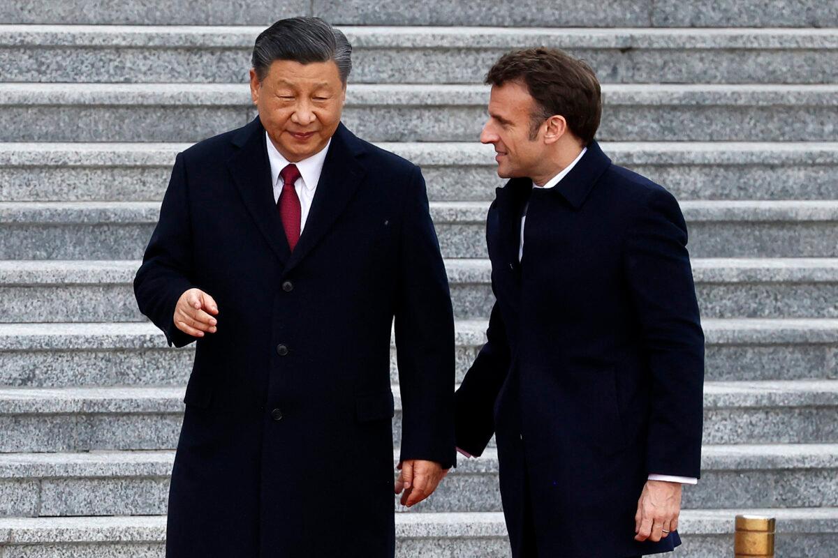 Chinese Communist Party’s leader Xi Jinping (L) talks with his French counterpart Emmanuel Macron as they arrive for the official welcoming ceremony in Beijing on April 6, 2023. (Ludovic Marin/AFP via Getty Images)