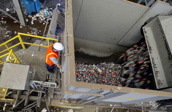 A worker watches as aluminum cans are emptied into a bailer at the Norcal Waste recycling facility in San Francisco on July 11, 2003. (Justin Sullivan/Getty Images)