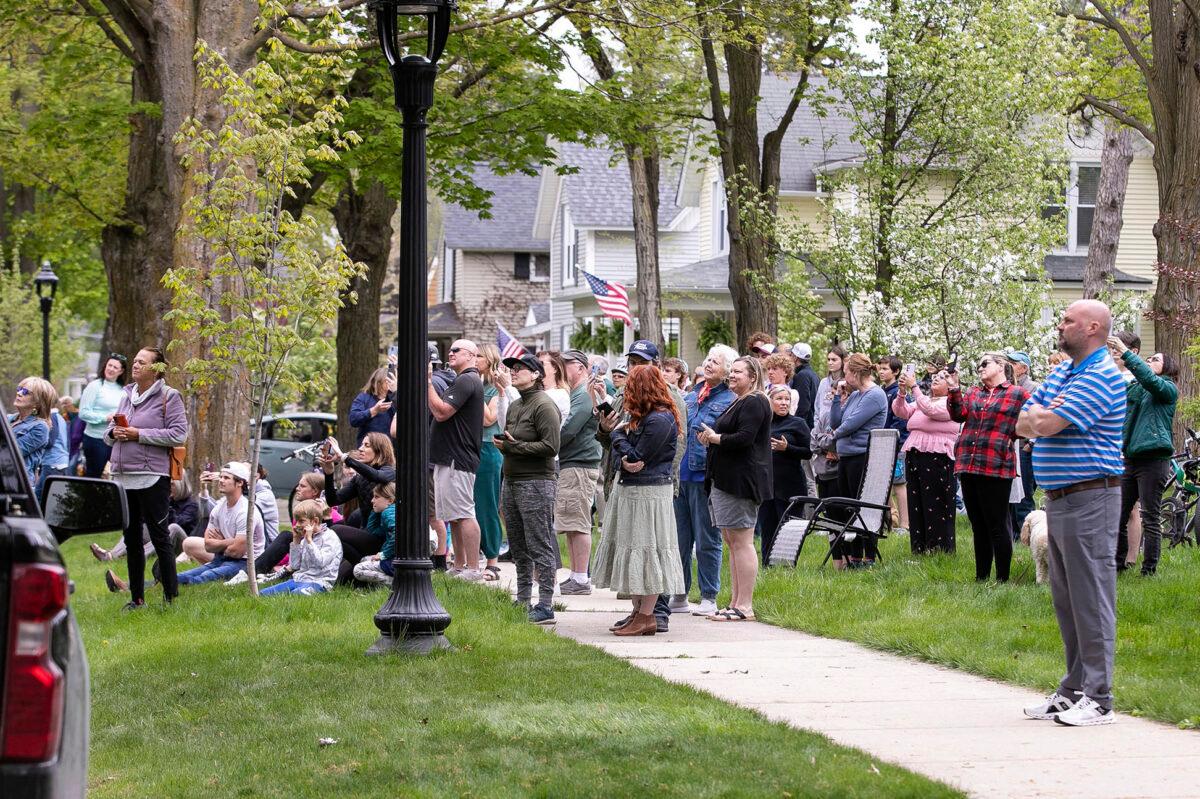 Onlookers watch as representatives from the Michigan Department of Natural Resources, DNR Conservation Officers, Traverse City Mich, Police, Traverse City Fire, and Traverse City Light and Power work to remove a black bear from a tree outside a Fifth Street home in Traverse City's Central Neighborhood on May 14, 2023. (Jan-Michael Stump/Traverse City Record-Eagle via AP)