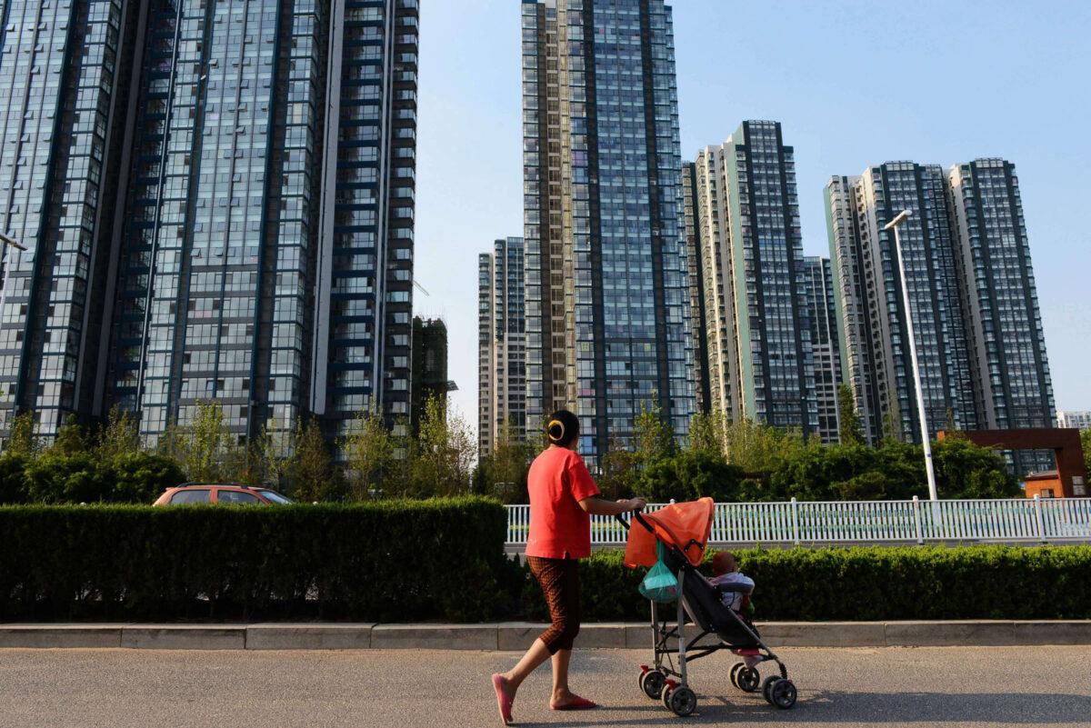 A woman walking with a baby on the street in Qingdao, east China's Shandong Province on Sept 1, 2013. (STR/AFP via Getty Images)