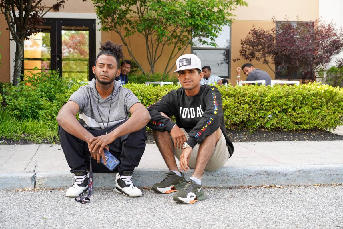 Illegal immigrants sit outside the Crossroads Hotel in Newburgh, N.Y., on May 15, 2023. (Cara Ding/The Epoch Times)