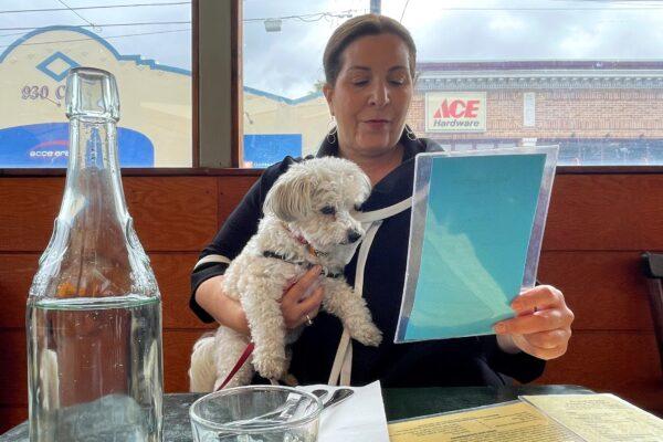 Ilana Minkoff checks out the menu with her dog JoJo Wigglebutt at a restaurant in San Francisco on May 5, 2023. (Haven Daley/AP Photo)