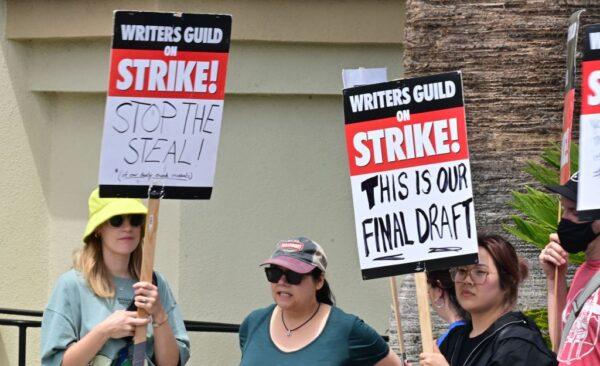 Writers hold signs while picketing in front of Paramount Studios in Los Angeles on May 15, 2023, as the strike by the Writers Guild of America enters its third week. The thousands of picketing writers say they are striking for better compensation in a field that has been disrupted by the streaming industry. Writers say they are looking for more stable working conditions and a better share of the profits generated by the rise of streaming. (Frederic J. Brown/AFP via Getty Images)
