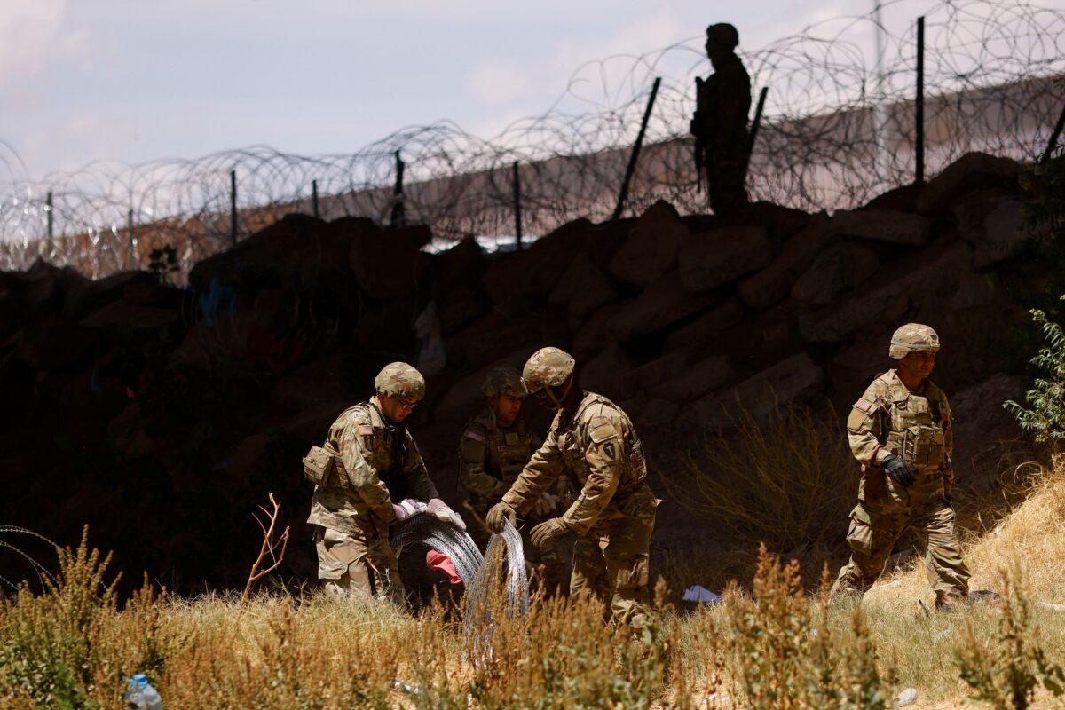 Members of the Texas Army National Guard extend razor wire to inhibit migrants from crossing, as seen from Ciudad Juarez, Mexico on May 13, 2023. (Jose Luis Gonzalez/Reuters)