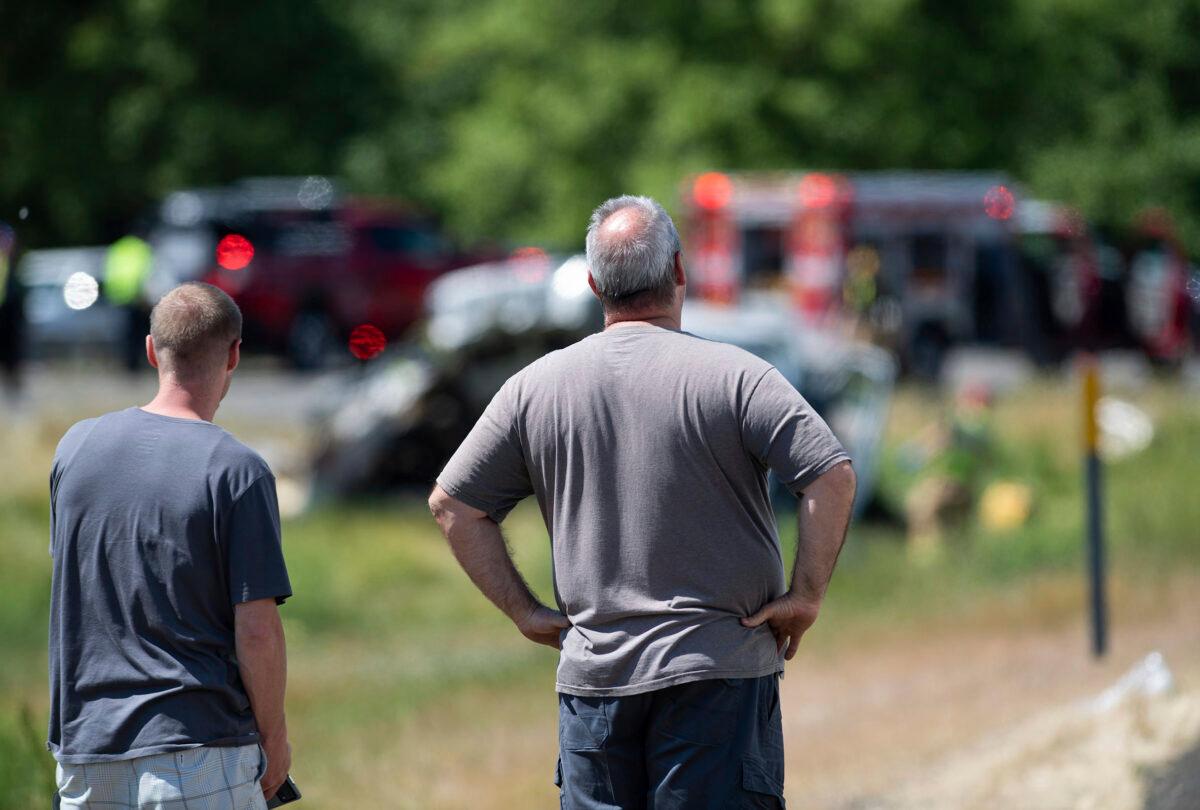 Joe Shipley (R) and another bystander watch emergency responders work at the scene of a multiple fatal crash along Interstate 5 in Albany, Ore., on May 18, 2023. (Alex Powers/Albany Democrat-Herald via AP)
