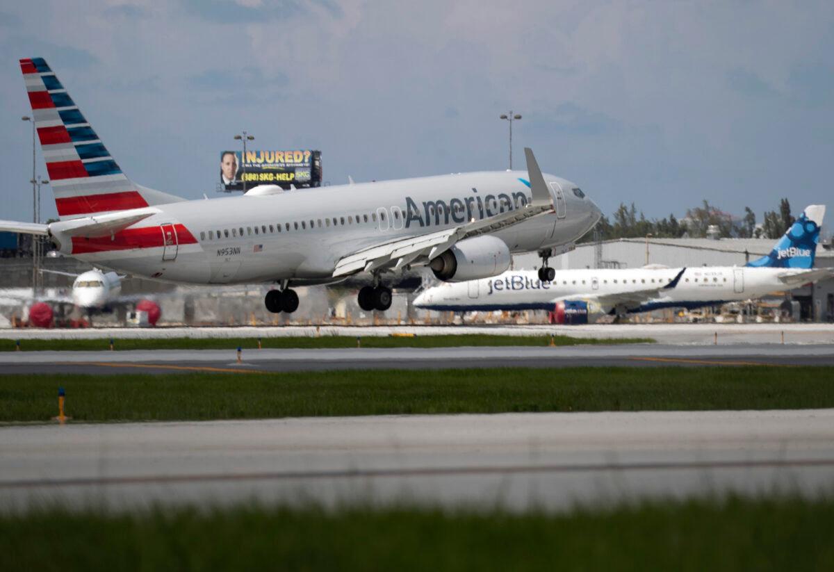 An American Airlines plane lands on a runway near a parked JetBlue plane at the Fort Lauderdale-Hollywood International Airport in Fort Lauderdale, Fla., on July 16, 2020. (Joe Raedle/Getty Images)