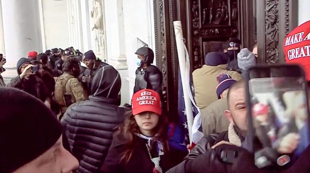 Megan Dawn Paradise wore a red, white, and blue tie, a Trump cape, and a MAGA cap and carried an American flag at the Capitol on Jan. 6, 2021. (U.S. Department of Justice/Screenshot via The Epoch Times)