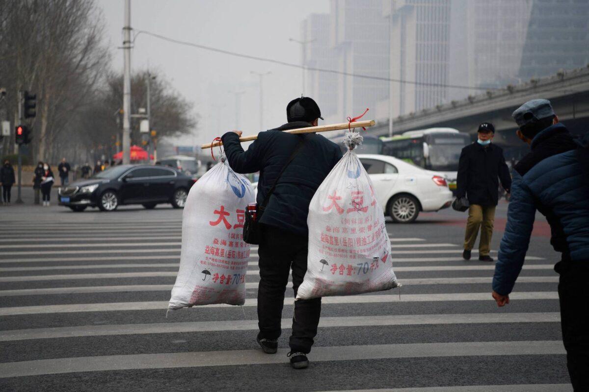 A migrant worker crosses a road after arriving on a long-distance bus in Beijing on March 10, 2021. (Greg Baker/AFP via Getty Images)