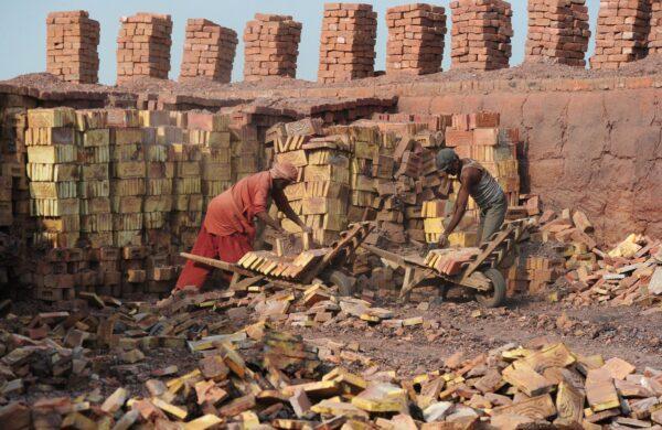 Pakistani labourers load bricks onto trollies at a brick kiln factory in Hyderabad, India, on Nov. 10, 2014. (Asif Hassan/AFP via Getty Images)
