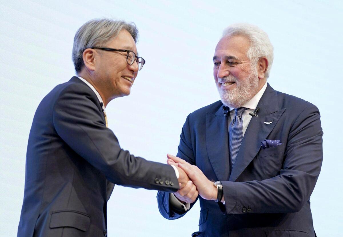 Toshihiro Mibe (L), president of Honda Motor Co., shakes hands with Lawrence Stroll, executive chairman of the Aston Martin team, during a press conference in Tokyo on May 24, 2023. (Kyodo News via AP)