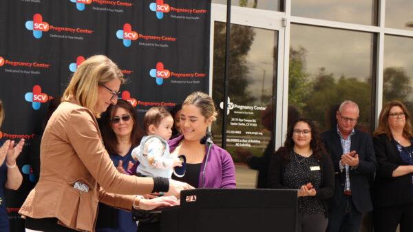 A patient of the Santa Clarita Valley Pregnancy Center, holding her son, speaks during a press conference demanding apologies from California Assemblywoman Pilar Schiavo (D-Chatsworth), who said the state’s pregnancy centers were unlicensed and deceptive, in Santa Clarita, Calif., on May 24, 2023. (Courtesy of California Family Council)