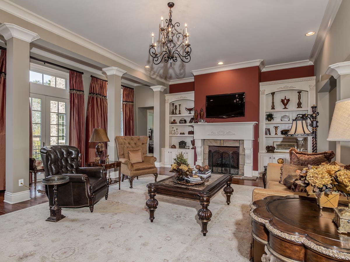 The very airy living room features extensive crown molding, decorative pillars, marble flooring, built-in bookshelves, and a fireplace. (Charlotte Virtual Home Tours/Premier Sotheby’s International Realty)