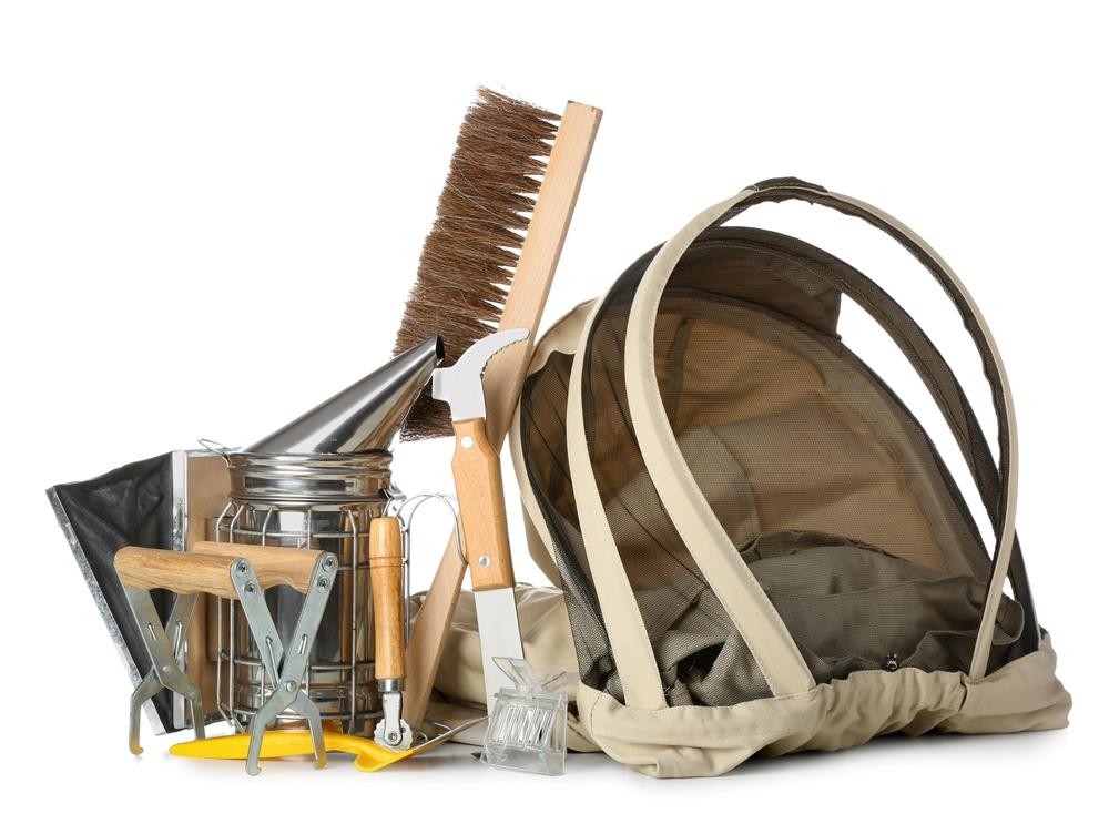 Beekeeping tools include a protective veil, a smoker, and a brush used to harvest the honey from the honey combs. (Pixel-Shot/Shutterstock)