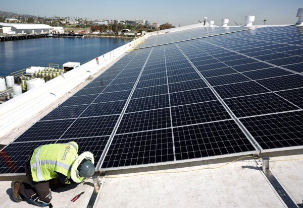 A worker installs solar panels during the completion phase of a four-acre solar rooftop atop AltaSea's research and development facility in the San Pedro neighborhood in Los Angeles on April 21, 2023. (Mario Tama/Getty Images)