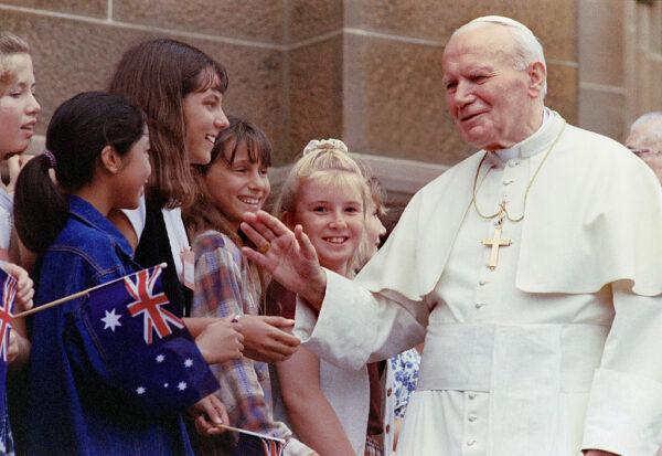 Pope John Paul II (R) is greeted on Jan. 19, 1995, by children at St Mary's Cathedral in Sydney before celebrating mass with the Sisters of St Joseph. (David Hancock/AFP via Getty Images)