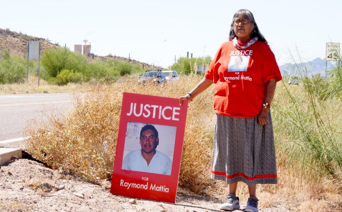 Mattias family spokeswoman Ofelia Rivas stands while propping a sign with a picture of Ray Mattia, who was shot and killed by U.S. Customs and Border Protection agents on May 18, 2023. The photo was taken during a protest in front of the Ajo Border Patrol Station in Why, Ariz., on May 27, 2023. (Allan Stein/The Epoch Times)
