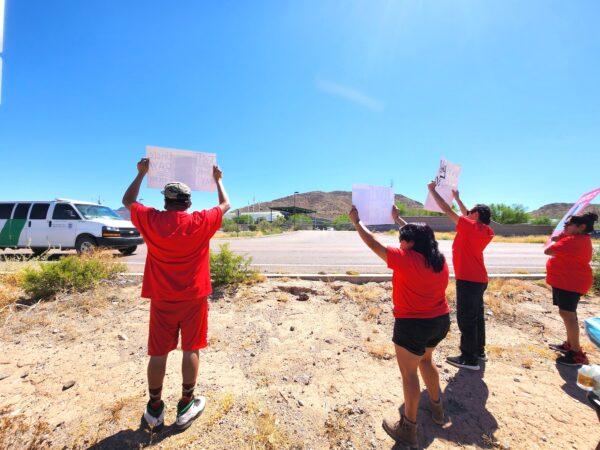 Protesters at a rally for Raymond Mattia flash placards at a passing Border Patrol vehicle in Why, Ariz., on May 27, 2023. (Allan Stein/The Epoch Times)