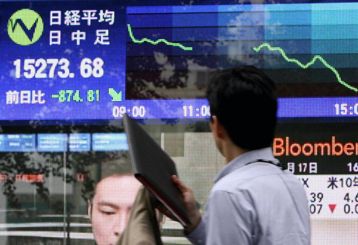 A passer-by looks at a stock price index board at the window of a security company headquarters in central Tokyo on Aug. 17, 2007. (Toshifumi Kitamura/AFP via Getty Images)
