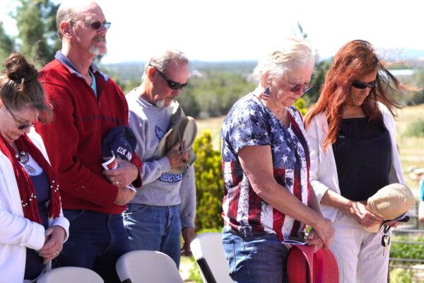 Visitors bow their heads in silence in Ash Fork Settlers Cemetery in Ash Fork, Ariz., on May 29, 2023. (Allan Stein/The Epoch Times)
