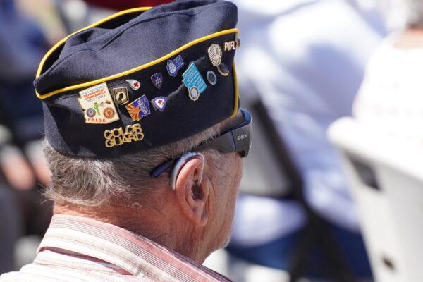 A veteran wears a cap laden with pins during a ceremony in Ash Fork Setters Cemetery on May 29, 2023. (Allan Stein/The Epoch Times)