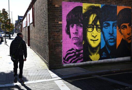 Pedestrians pass a mural depicting members of British rock band The Beatles (L-R) Ringo Starr, John Lennon, Paul McCartney, and George Harrison on the side of a building in Liverpool, northwest England on Oct. 13, 2020. (Paul Ellis/AFP via Getty Images)