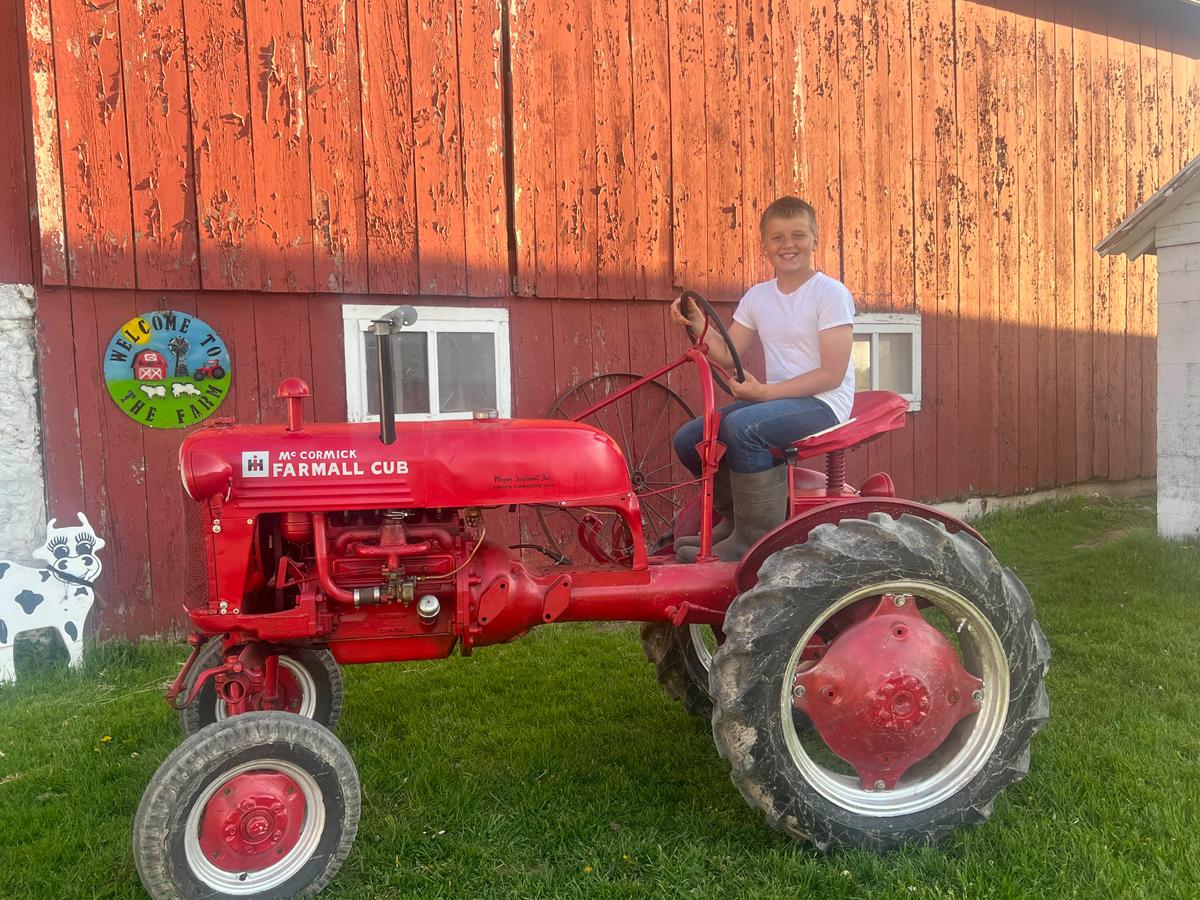 Caleb with his 1948 McCormick Farmall Cub he purchased on May 2 for $2,800 with money saved from eight years' worth of chores. (Courtesy of Jill Bergner)