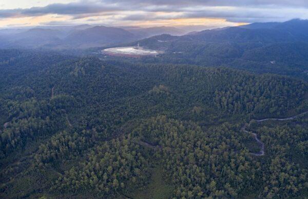 A 2023 landscape photo shows the Rosebery mine, a tailings dam in the background, and the Tarkine rainforest in the foreground. (Courtesy of Bob Brown Foundation)