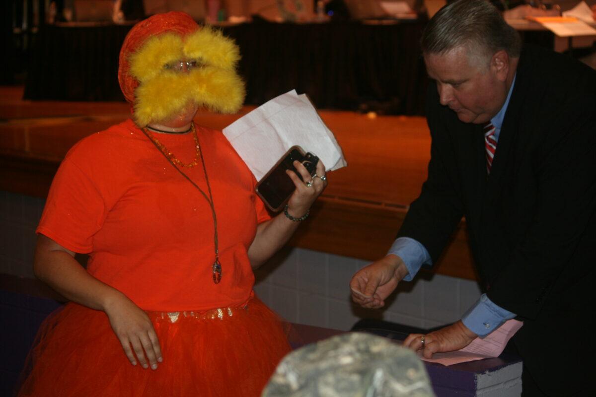 Jenna Barbee, a fifth grade teacher from Winding Waters K-8 in Hernando County, Fla., appears dressed as "The Lorax," a Dr. Seuss character, as she submits the required pink form to speak during public comments at the school board meeting on May 30, 2023. (Patricia Tolson/The Epoch Times)