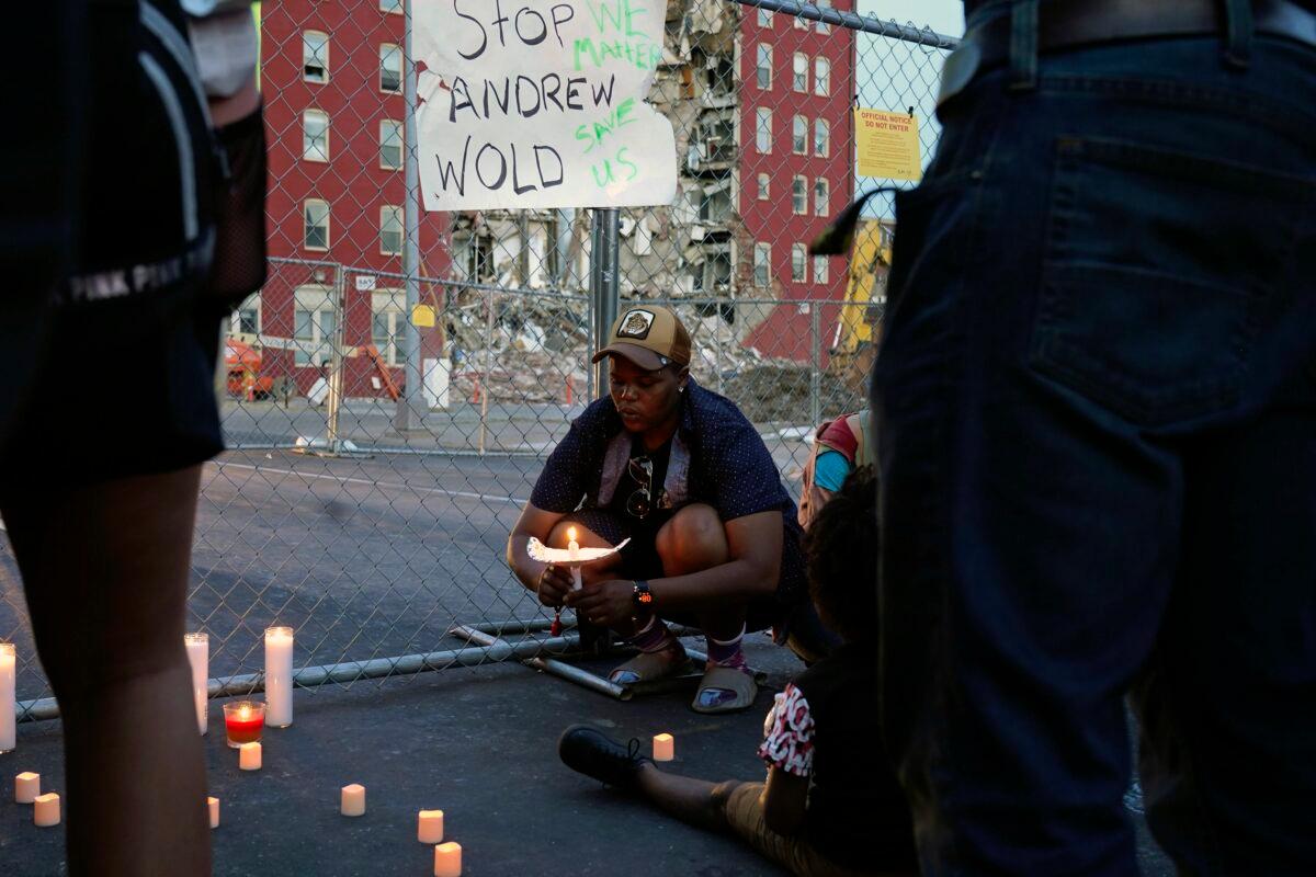 Raquel Sipp kneels with a candle at the scene of where an apartment building partially collapsed two days earlier, in Davenport, Iowa, on May 30, 2023. (Erin Hooley/AP Photo)