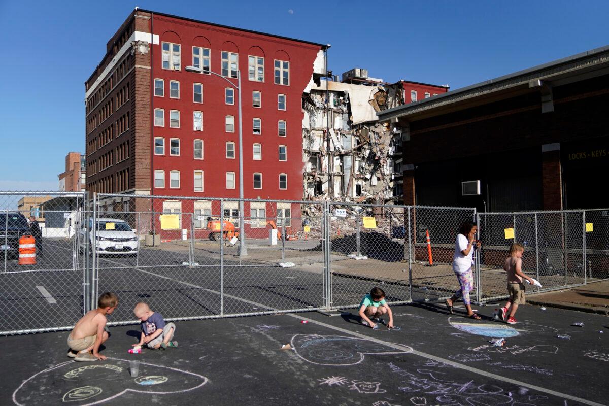 Children draw on the ground with chalk at the scene where an apartment building partially collapsed on Sunday afternoon in Davenport, Iowa, on May 30, 2023. (Erin Hooley/AP Photo)