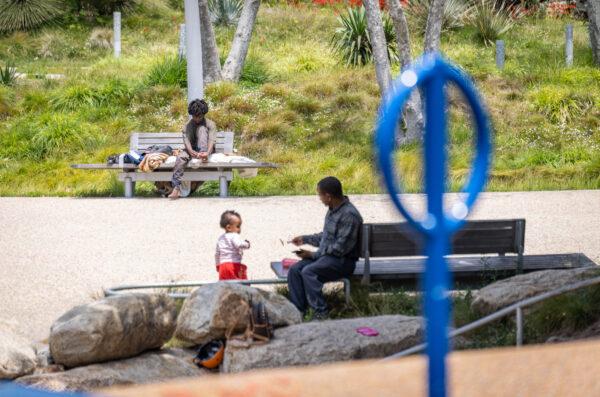 A family uses a playground near a homeless man in Santa Monica, Calif., on June 2, 2023. (John Fredricks/The Epoch Times)