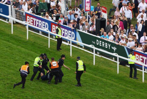 A protestor is removed from the race track by police officers during the 13:30 Betfred Derby Action at Epsom Downs Racecourse in Epsom, Britain, on June 3, 2023. (Matthew Childs/Images via Reuters)