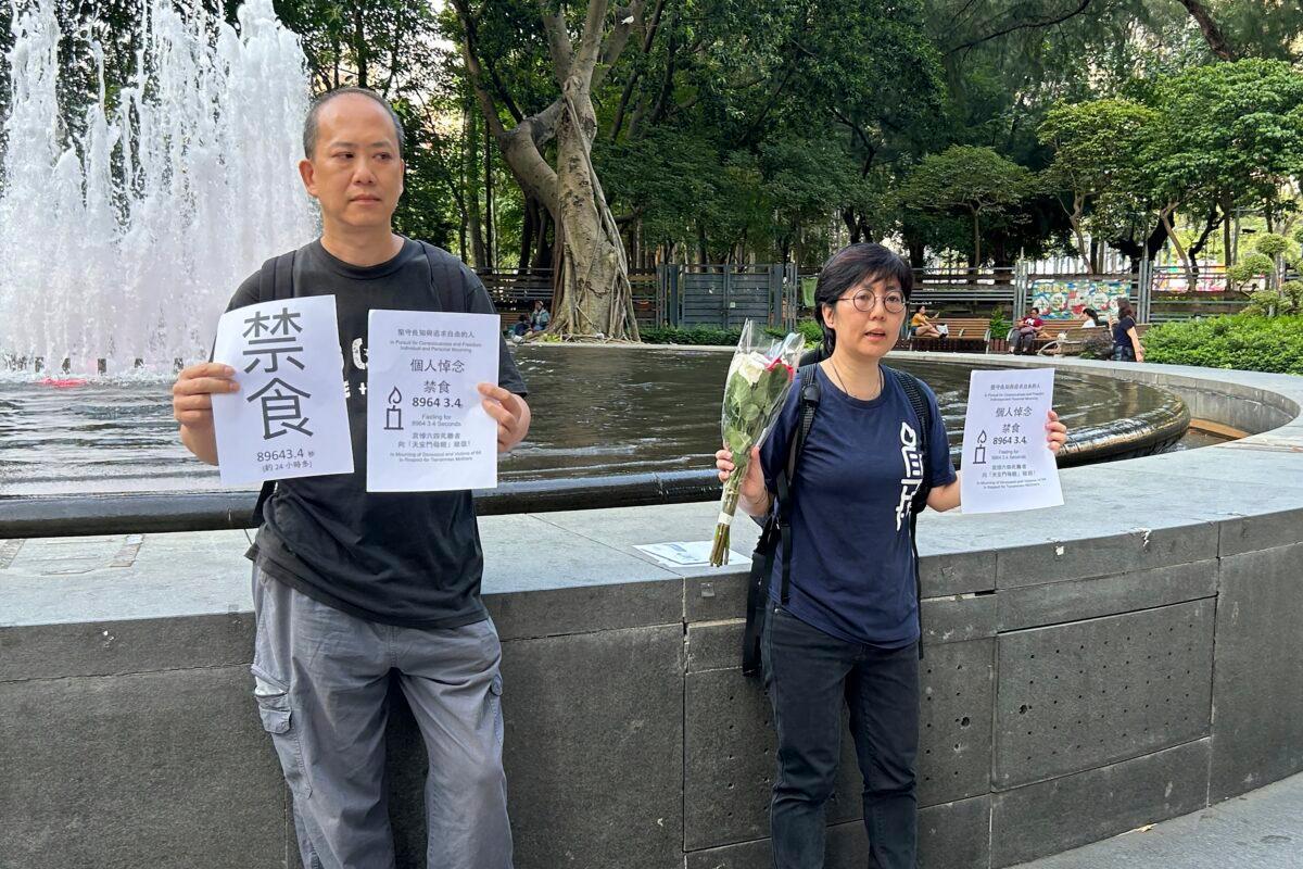 Tiananmen activists Kwan Chun-pong (L) and Lau Ka-yee (R) hold up papers with the word Fasting and details of their plan to fast for about a day at the entrance of Hong Kong's Victoria Park on June 3, 2023. (Kanis Leung/AP Photo)