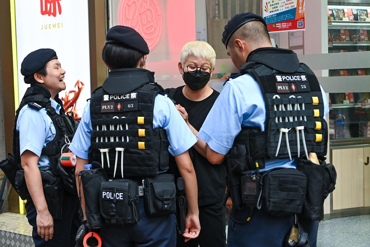 Ms. Cheung, a woman wearing a black mask and tee, was stopped and searched by the police. (Benson Lau/The Epoch Times)